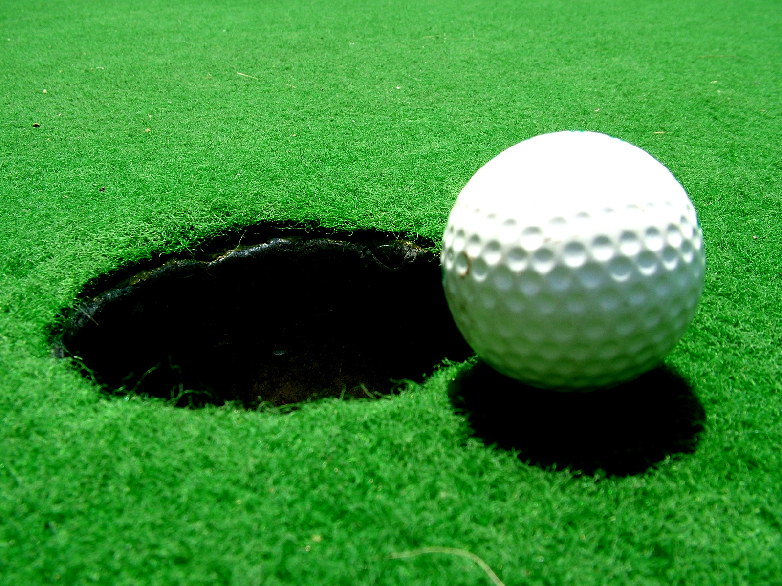 Golf ball near the cup on green